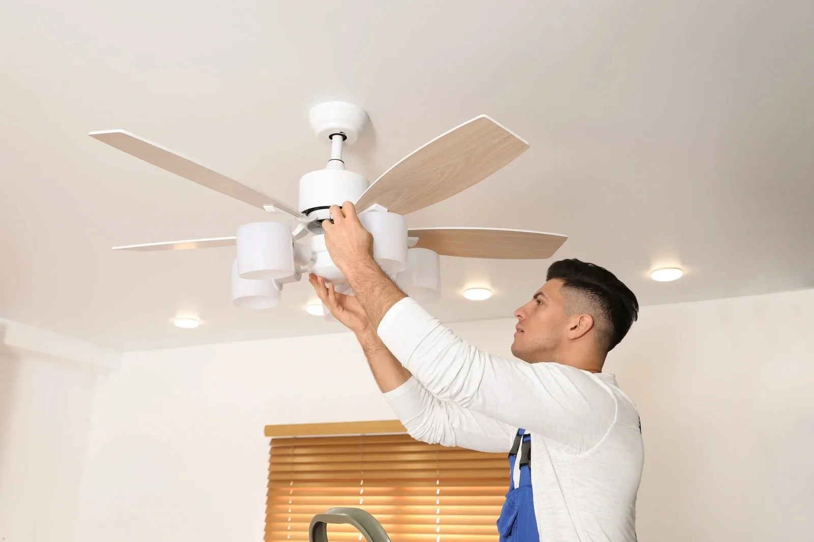 Licensed electrician installing a ceiling fan in a home