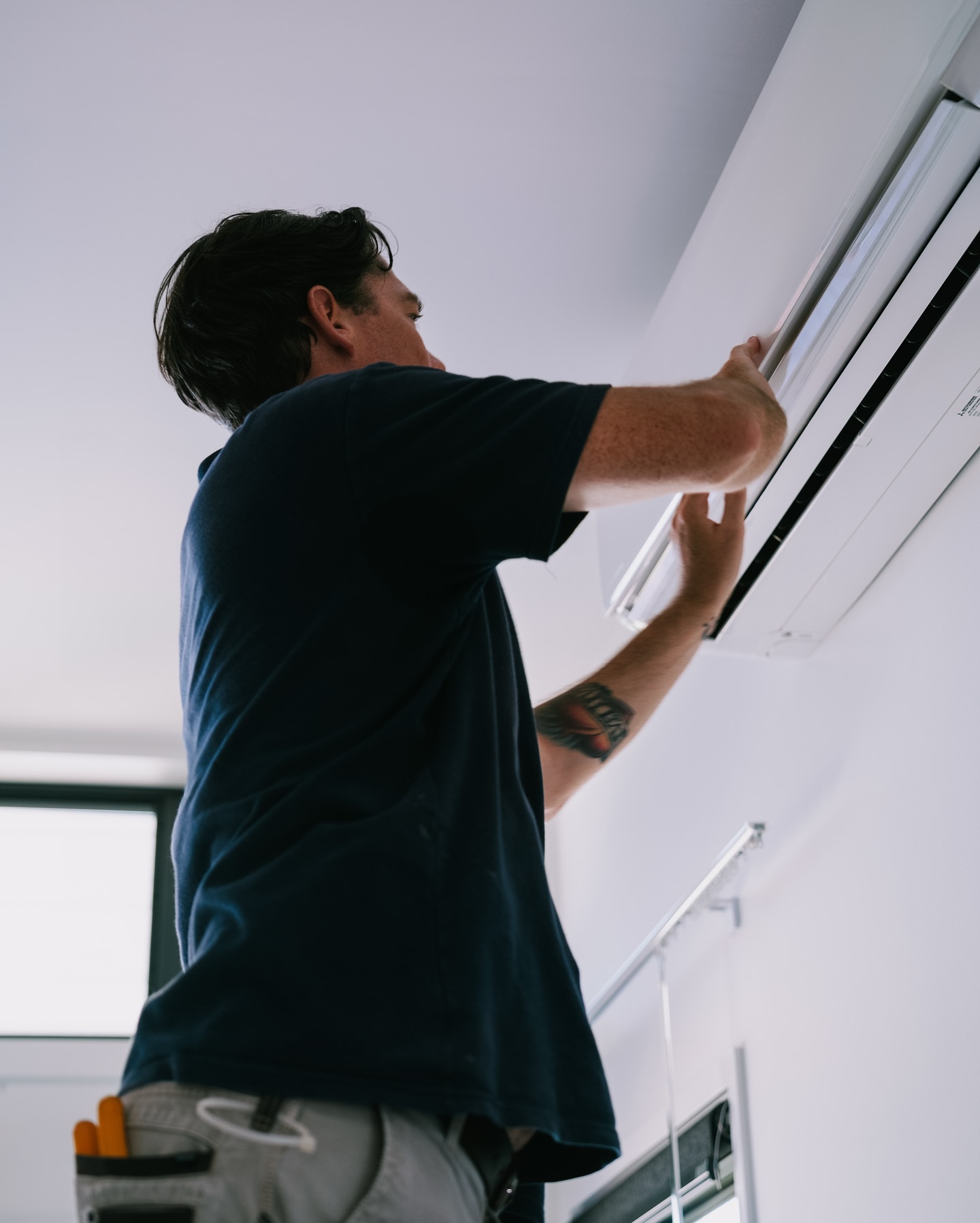 Electrician installing a split system air conditioner indoor unit