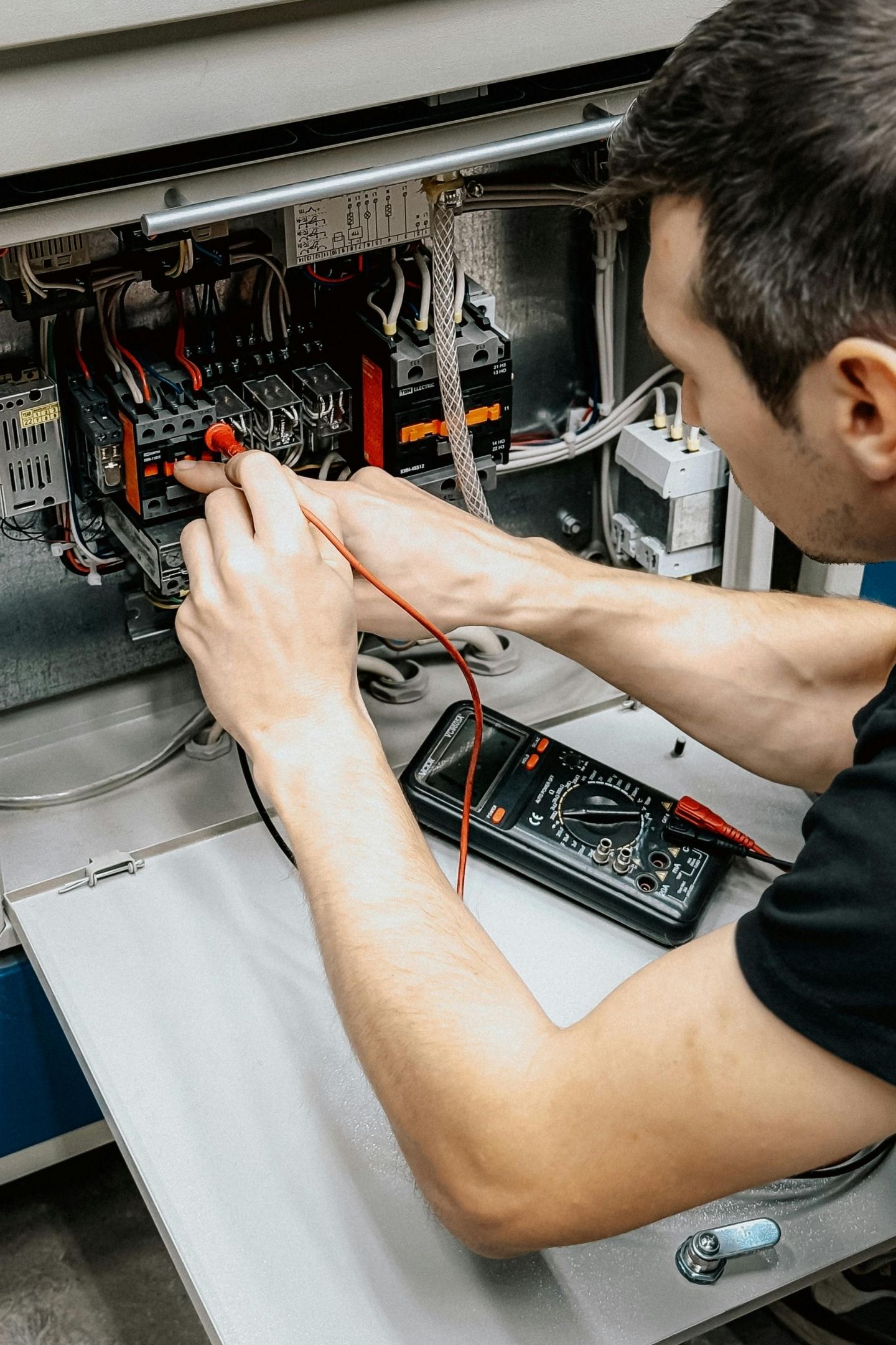 Electrician fault-finding inside a switchboard during an emergency call-out, Gold Coast